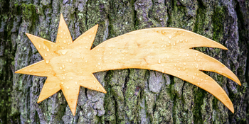 Weihnachtsstern aus Holz an einem Baum.